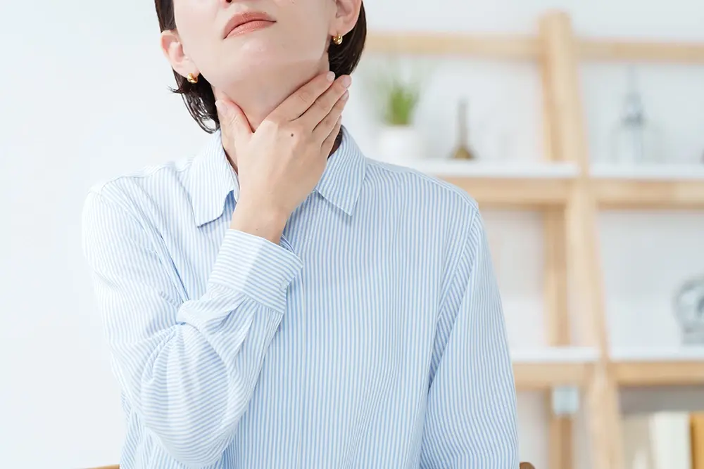 A woman experiencing a persistent sore throat as a sign of chronic laryngopharyngeal reflux