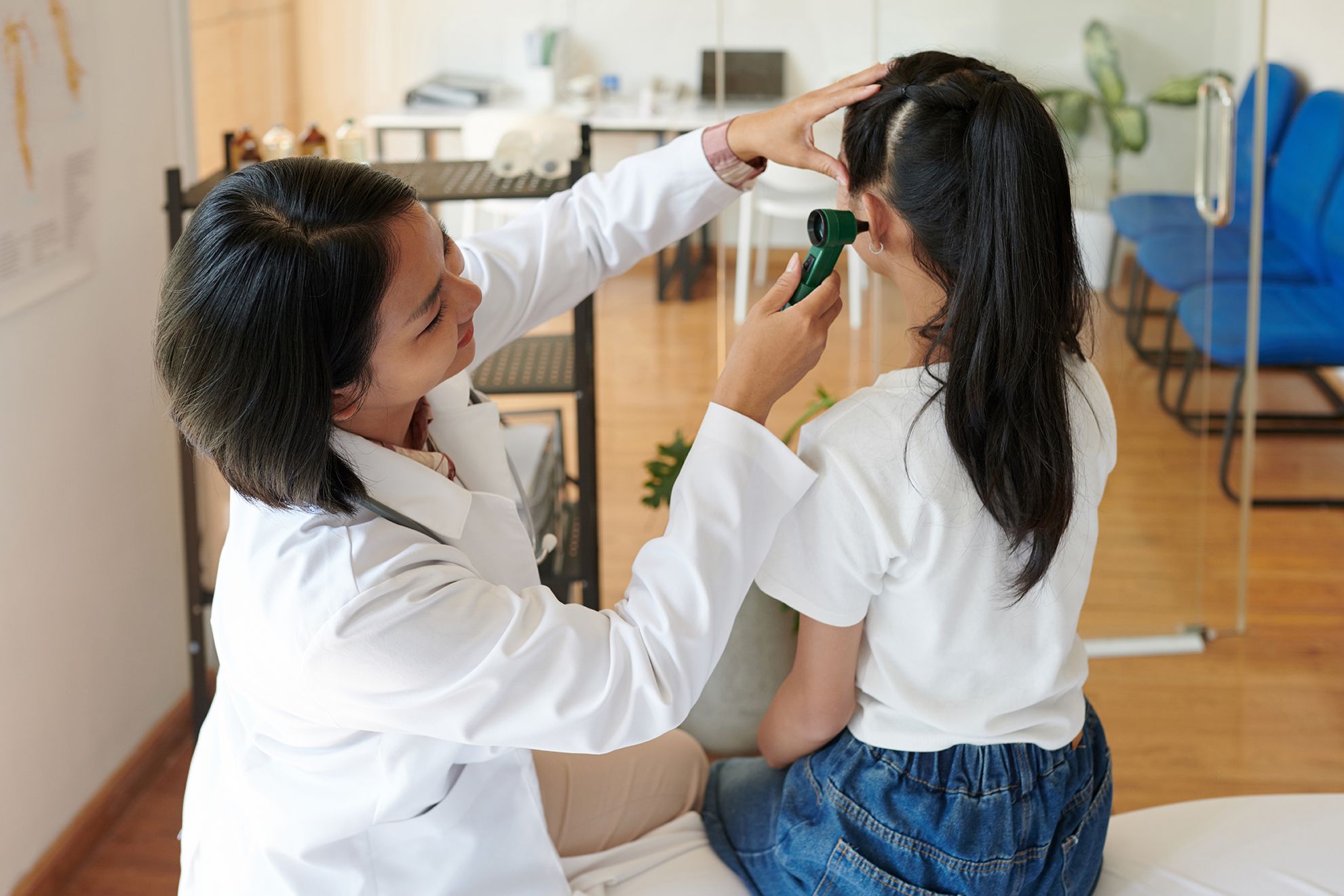 A doctor treating a girl with an ear infection